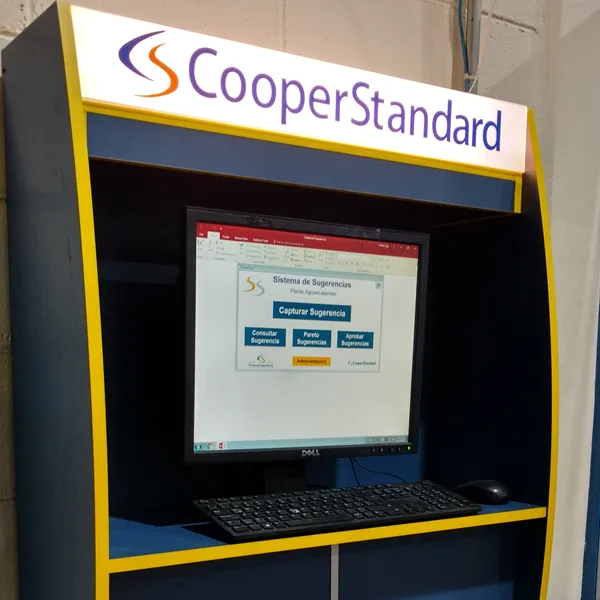Kiosco con computadora, marco azul y amarillo y logotipo de Cooper Standard.
