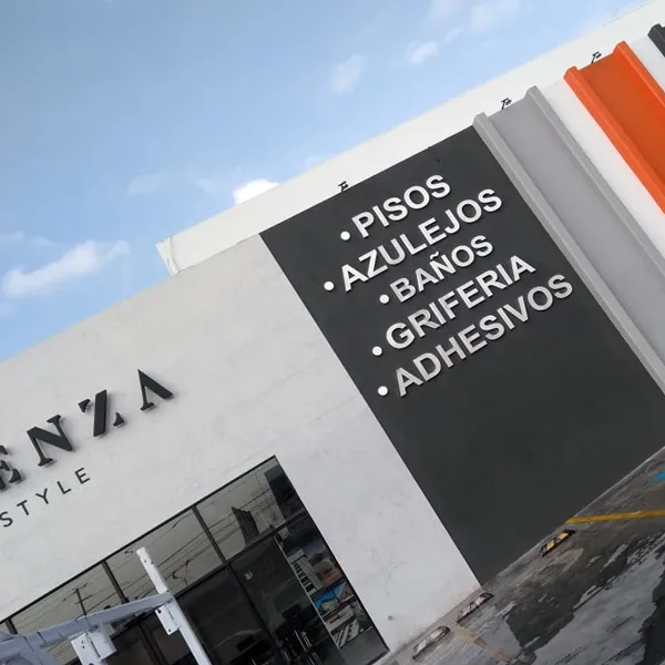 Fachada blanca con rótulo negro que anuncia pisos, azulejos, baños, grifería y adhesivos.